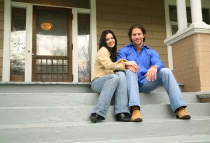 Photo of a handsome couple sitting on the porch of their home.
