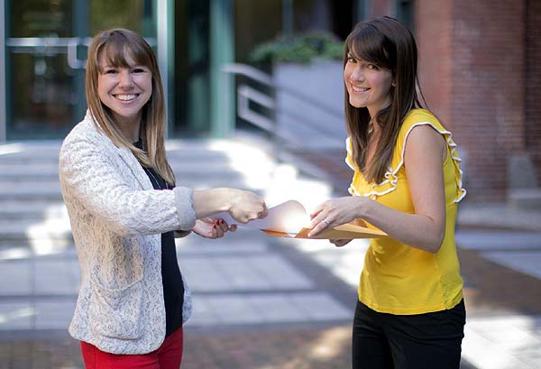 Photo of one woman smiling while another hands her a paper - Guide to a Smooth and Successful Home-Buying Process