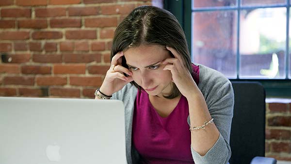 Photo of a woman stressed out in front of a laptop computer