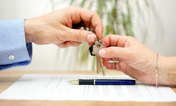 Photo of a man handing house keys to a woman
