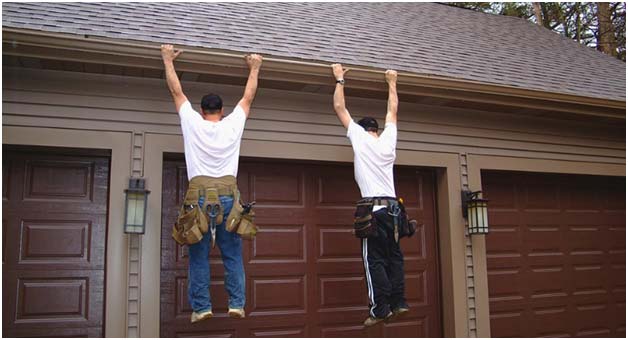Photo of two men hanging on a home's gutters.