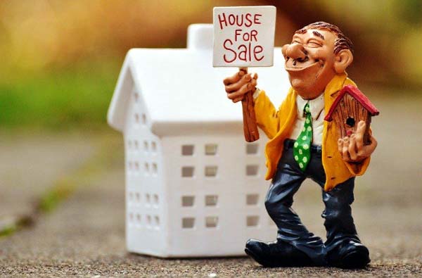Photo of a figure holding a House for Sale sign