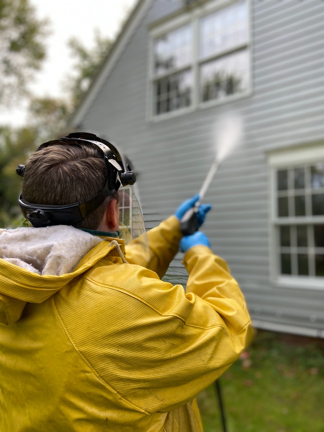 Photo of a man power washing a house