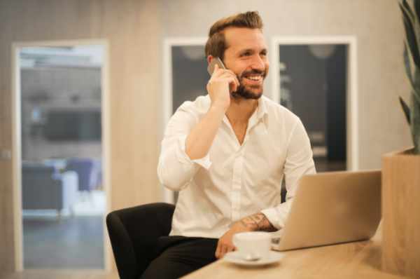 Photo of a man working with a cellphone and laptop