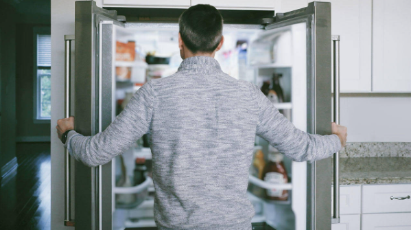 Photo of a man opening a refrigerator in his kitchen