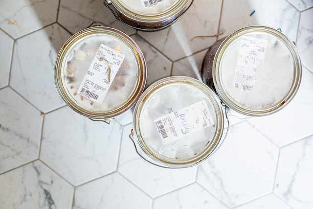 Photo of an overhead view of paint cans resting on a tile floor