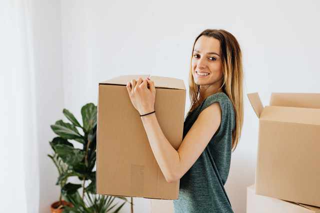 Photo of a woman carrying a cardboard box on moving day