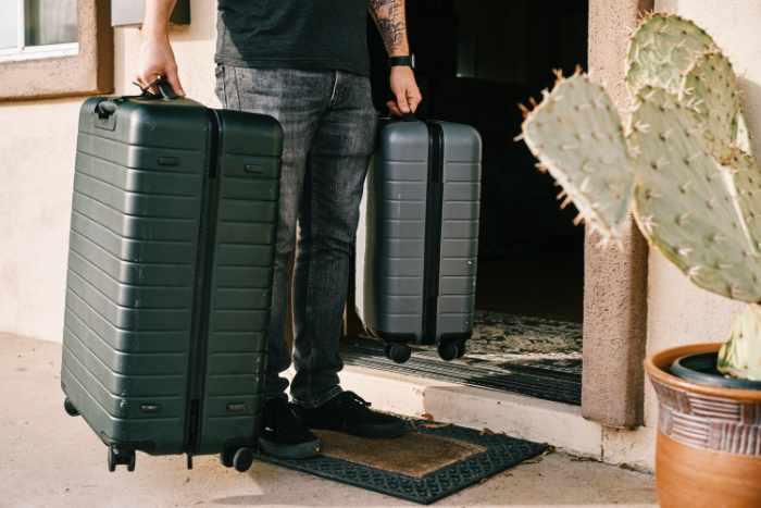 Photo of a man bringing two suitcases into his apartment - Apartment Living Essentials