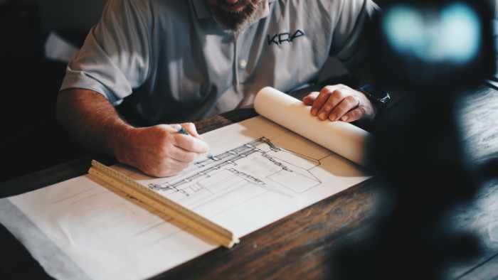 Photo of an architect drafting construction plans on a table
