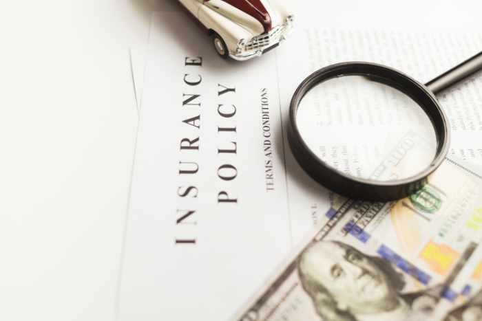 Photo of a magnifying glass on top of papers and money - Benefits of Home Insurance