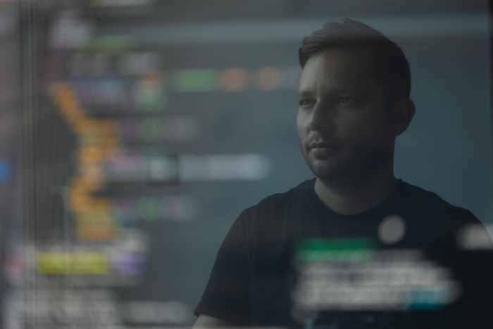 Photo of a man shown in the reflection of a computer screen