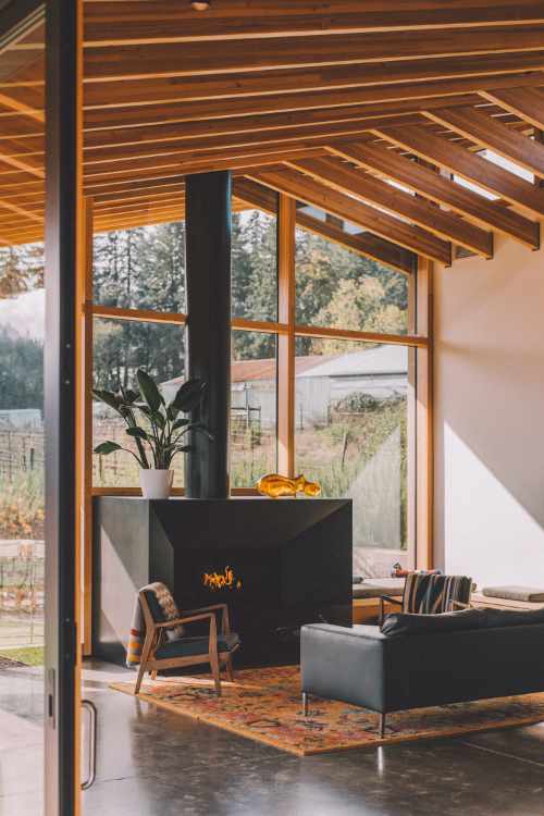 Photo of an inviting living room with metal fireplace, wood beams and lots of glass windows