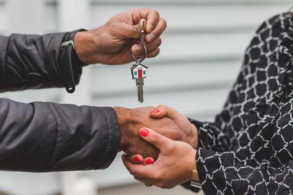 Photo of a man giving a woman a key to a house