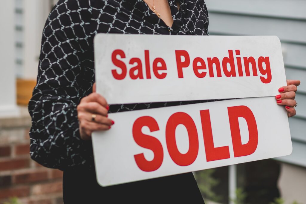 Photo of an agent holding a Sale Pending sign and a Sold sign