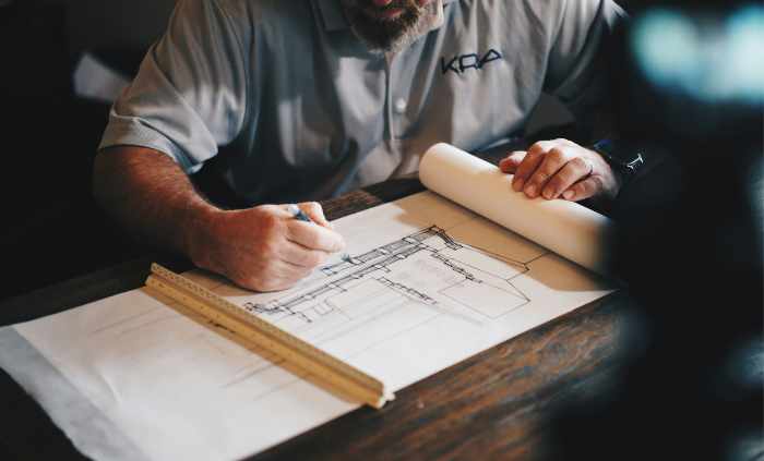 Photo of a builder drafting a plan of a new building - 10 Steps to a Hassle-Free Commercial Building Project