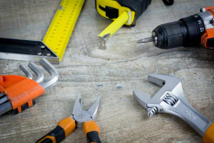 Photo of home maintenance tools such as a drill, wrench, tape measure and more - The Long-Term Benefits of Preventative Home Maintenance and Repair