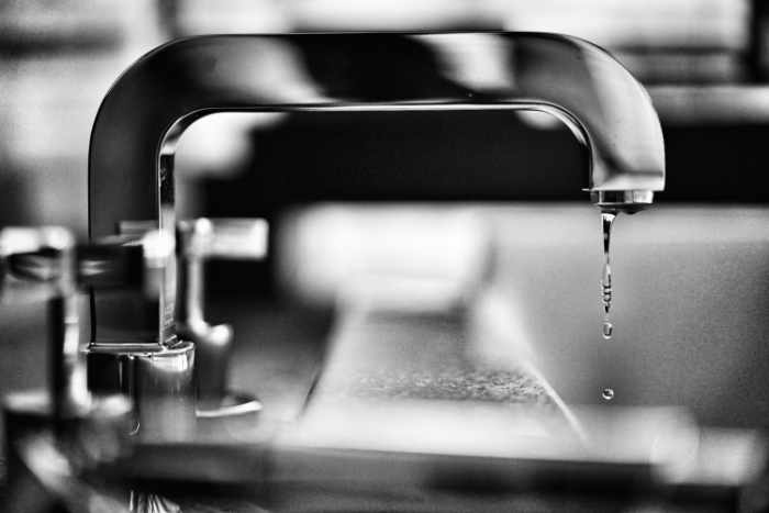 Black and white photo of a faucet dripping - 5 Ways Seasonal Changes Can Affect Plumbing