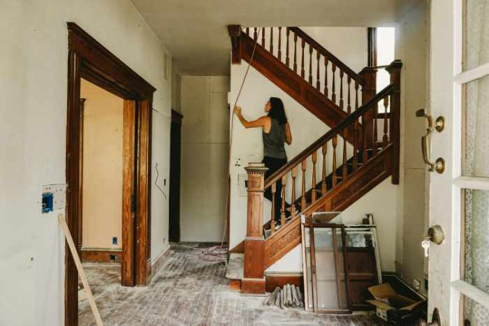 Photo of a woman painting near a staircase - From Fixer-Upper to Showstopper: 6 Steps to Transform Your Investment Property