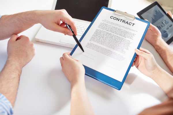 Photo of two people working on a contract with a computer and tablet - How to Write a Verification of Rent Letter: A Detailed Step-by-Step Guide