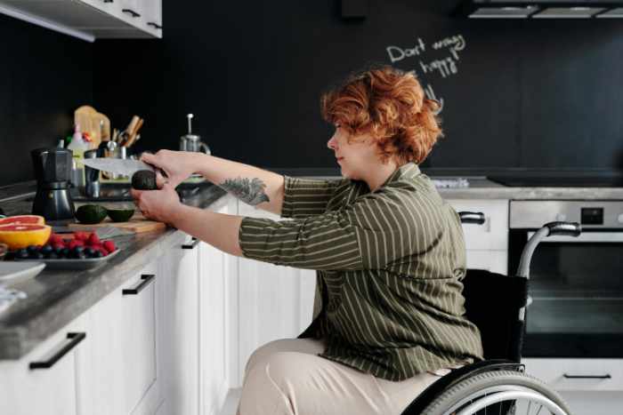 Photo of a woman in a wheelchair making a meal in her kitchen