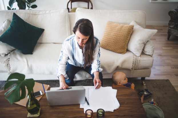 Photo of a woman working from her couch with a laptop and papers - A Homeowner's Estate Planning Checklist: Protecting The Property You Leave Behind