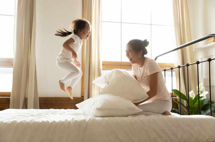 Photo of a small girl jumping on a bed with her mother - Where Allergens Hide: The Hotspots Inside Family Homes